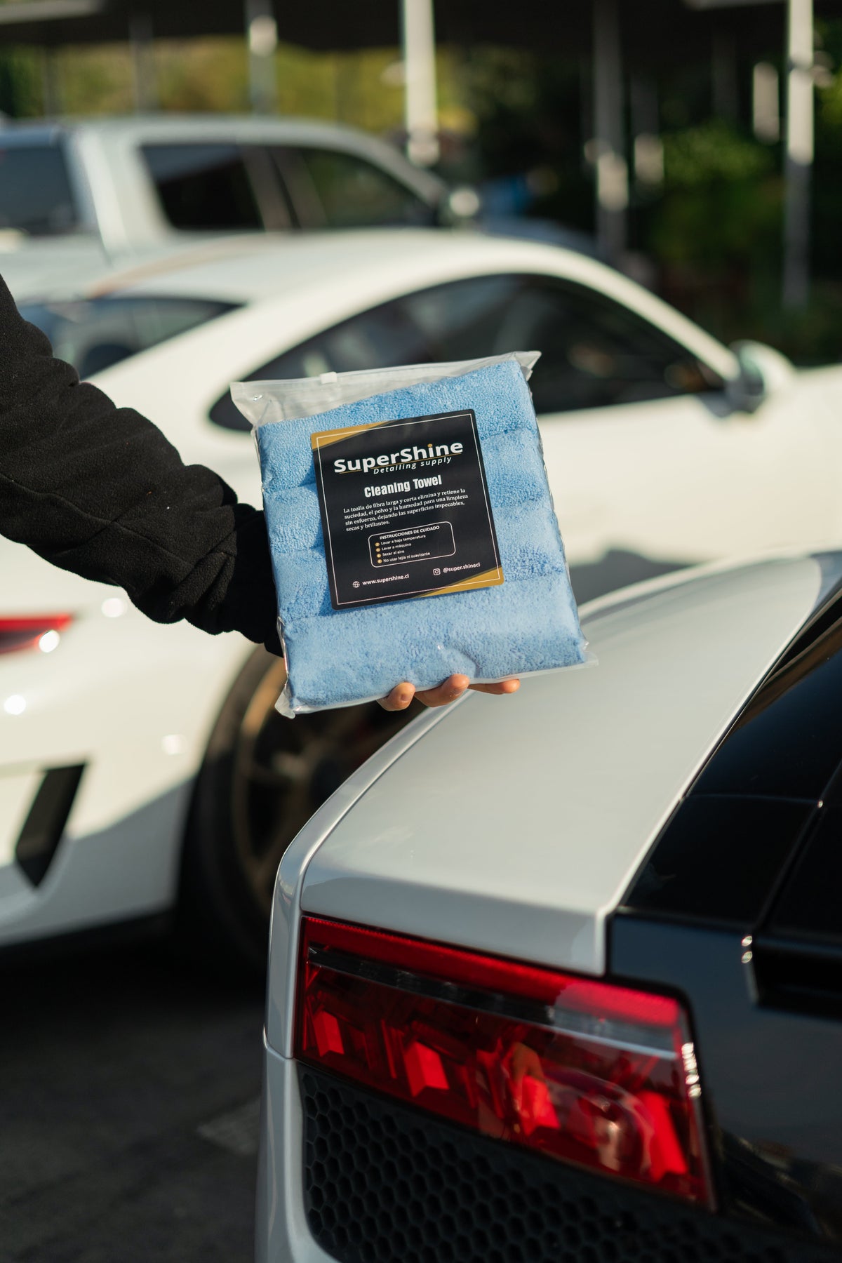 Pack de paños de microfibra Supershine sostenido junto a un auto