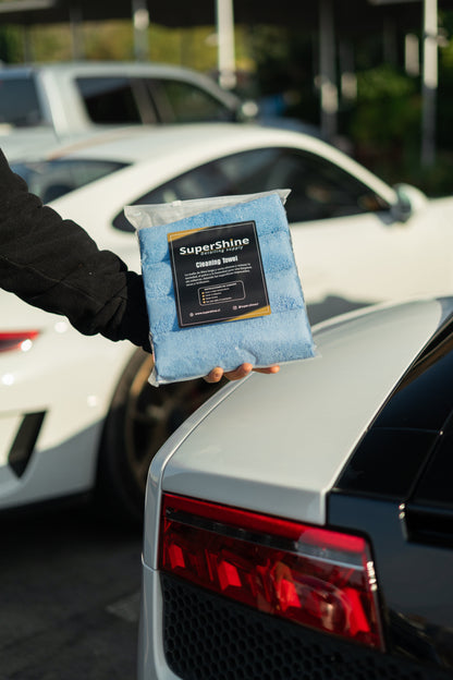 Pack de paños de microfibra Supershine sostenido junto a un auto